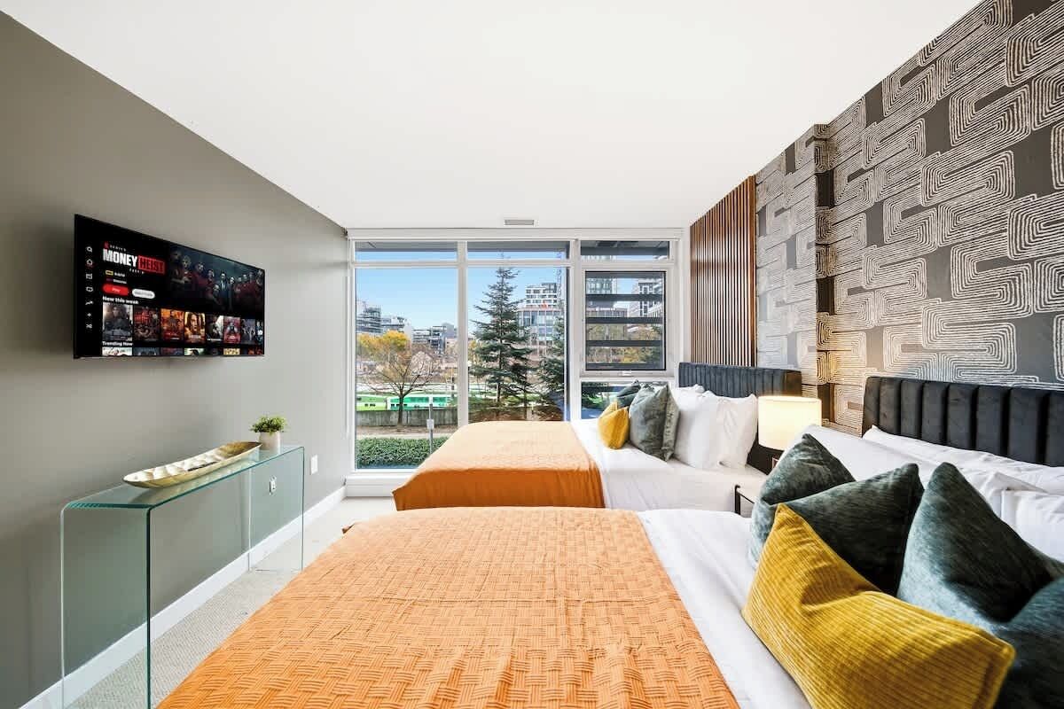 Ein modernes Hotelzimmer mit großem Fenster, einem wandmontierten Flachbildfernseher und einem strukturierten Wanddesign.