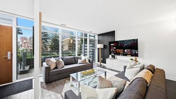 Ein modernes Wohnzimmer mit Sofa, Couchtisch und Fernseher.