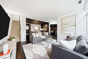 Un salon moderne avec un canapé, une table basse et un escalier menant à une autre pièce.