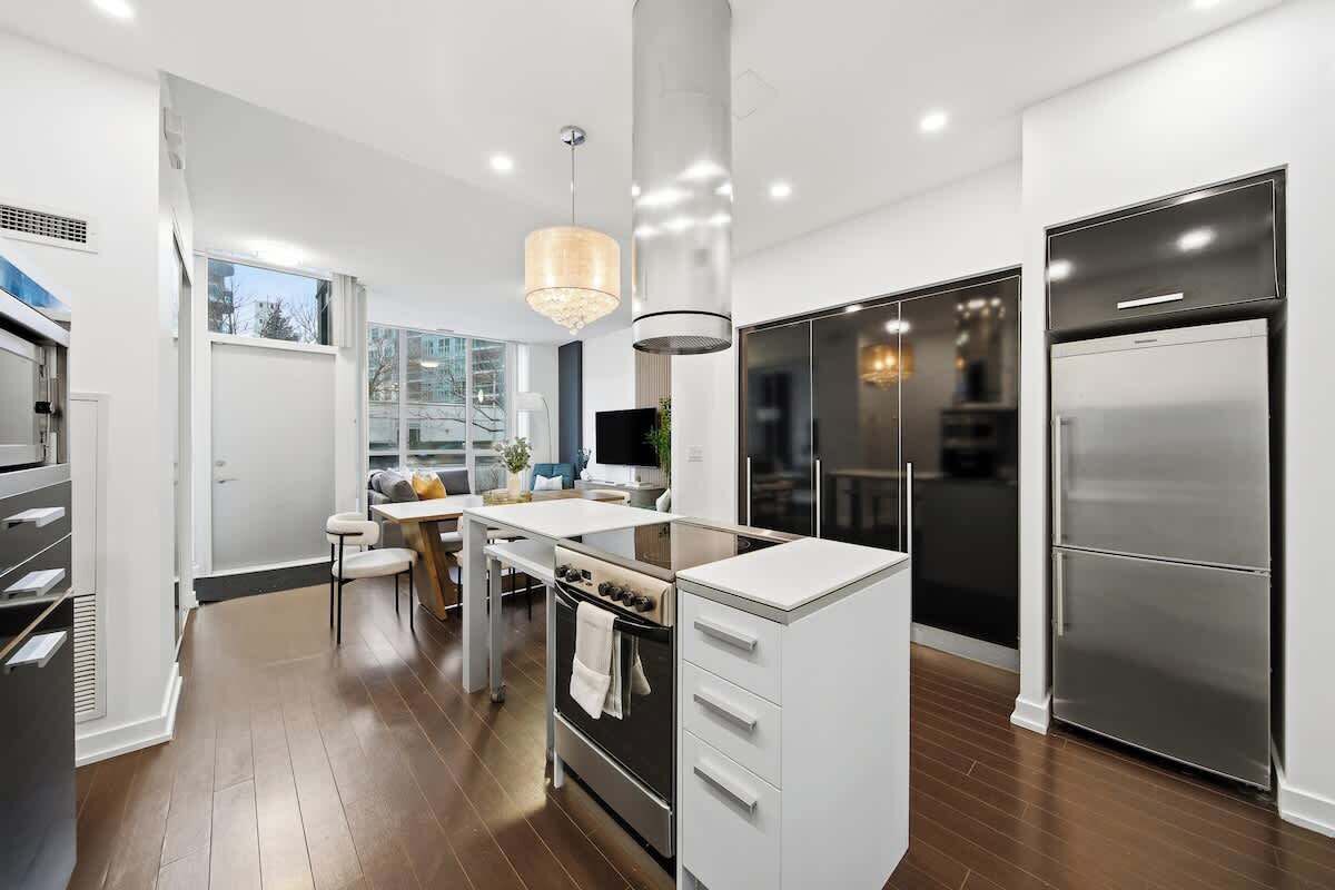 A modern kitchen with a central island, stainless steel appliances, and a pendant light.