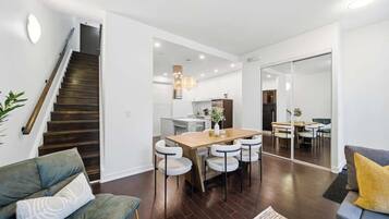 A modern interior with a staircase, dining area, and seating.