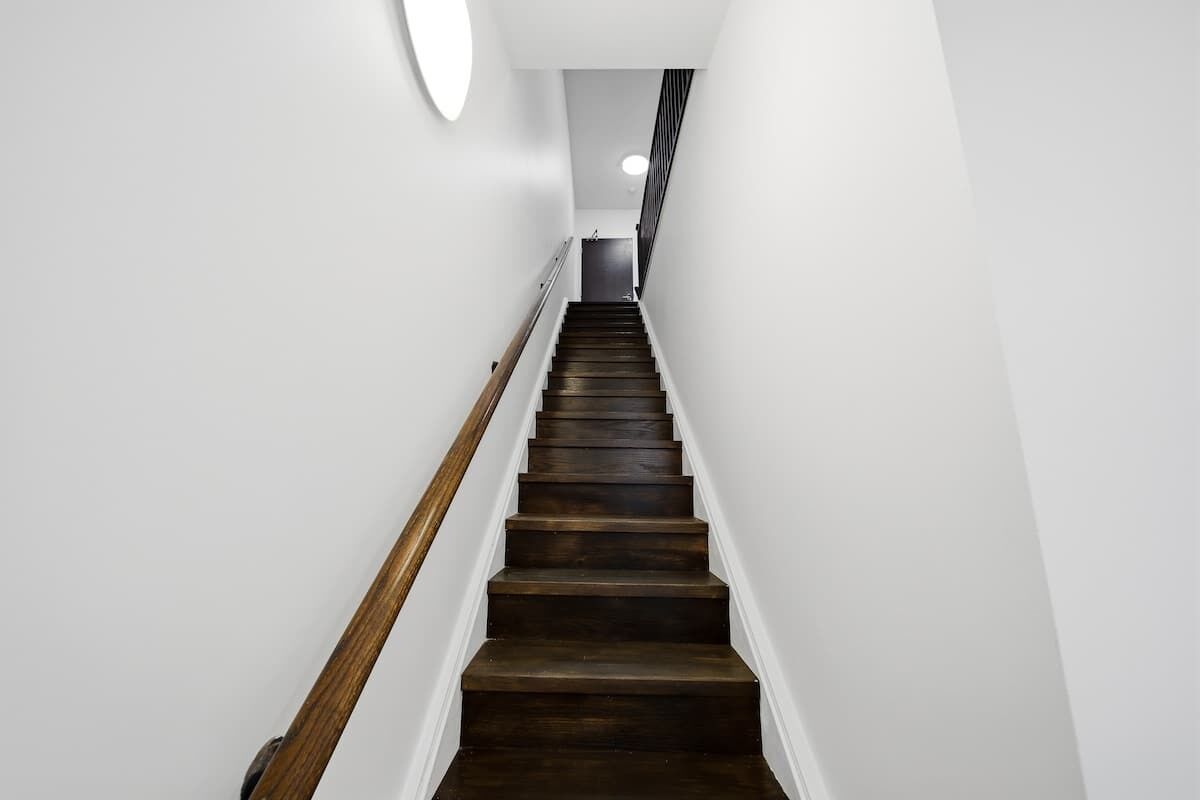 A staircase with wooden handrails and white walls.