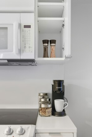 Une cuisine équipée d’un four à micro-ondes, d’une machine à café et de salières et de poivrières posées sur le comptoir.