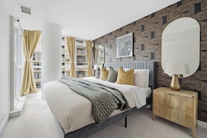 Ein modernes Schlafzimmer mit einem großen Bett, einem Nachttisch aus Holz und einer Wand mit Muster.