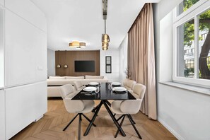 A modern dining area with a black table, white chairs, and a large window with curtains. - Designer Flagship for 6 - by Presidential Palace (Bratislava)