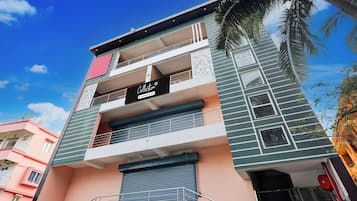 Un edificio de varios pisos con balcones, un letrero de servicio de la empresa y un cielo despejado.