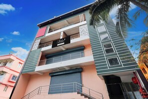 A multi-story building with balconies, a company-serviced sign, and a clear sky.