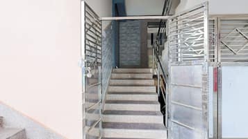 Una escalera que lleva a un rellano con una reja metálica y una puerta de cristal.