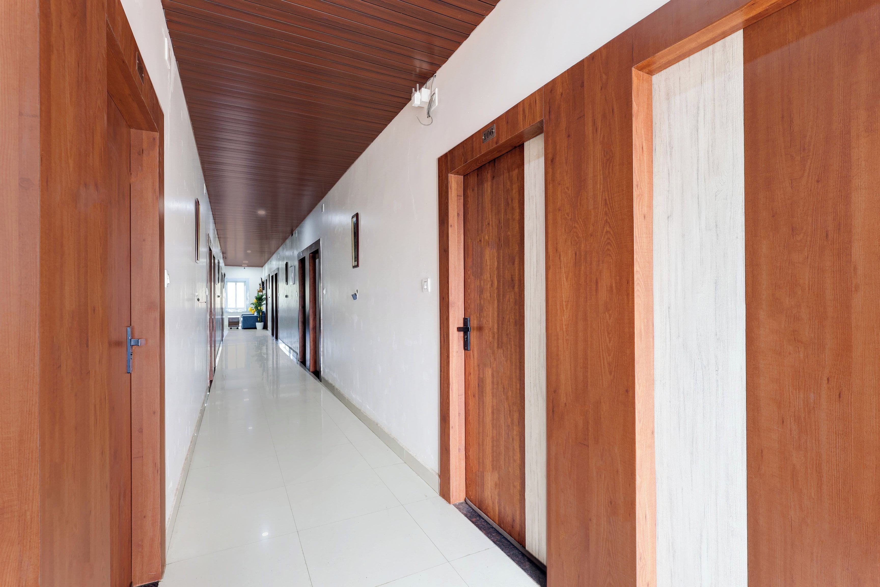 A long hallway with wooden doors and a tiled floor.
