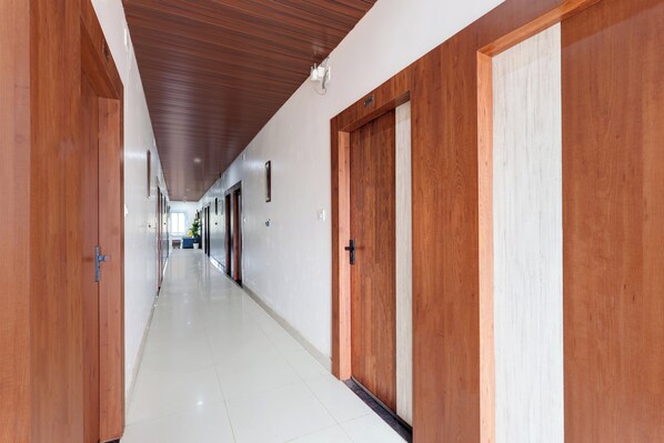 A long hallway with wooden doors and a tiled floor.