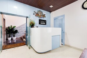 A reception area with a reception desk, a wall-mounted sign, and a staircase leading to an upper level.