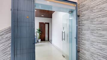 Un pasillo con una puerta de vidrio, una puerta de madera y una planta en maceta.