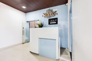 A reception area with a glass partition, a reception desk, a wall-mounted sign, and a decorative wall piece.