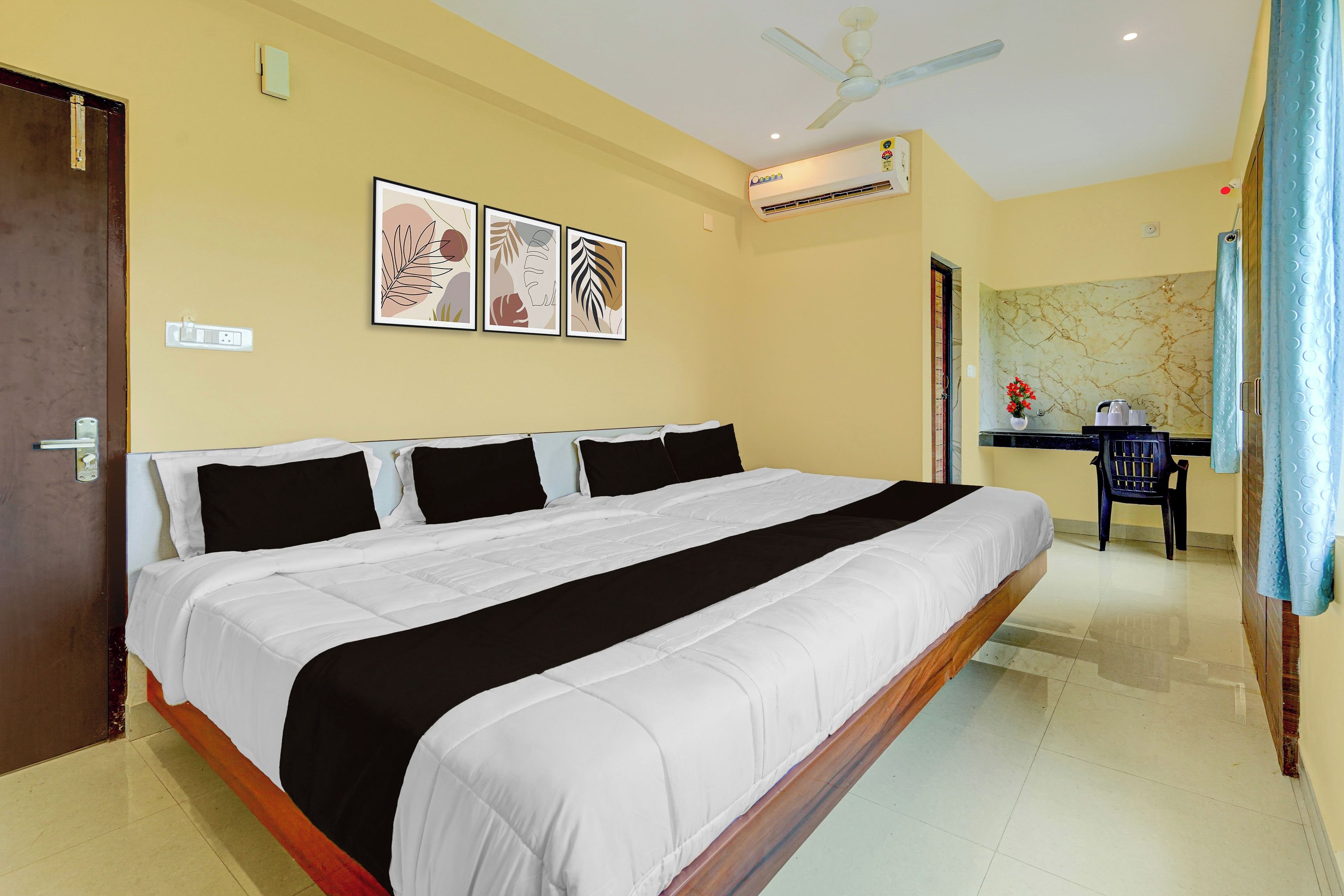 Habitación de hotel con una cama grande, un escritorio con silla, ventilador de techo y aire acondicionado instalado en la pared.