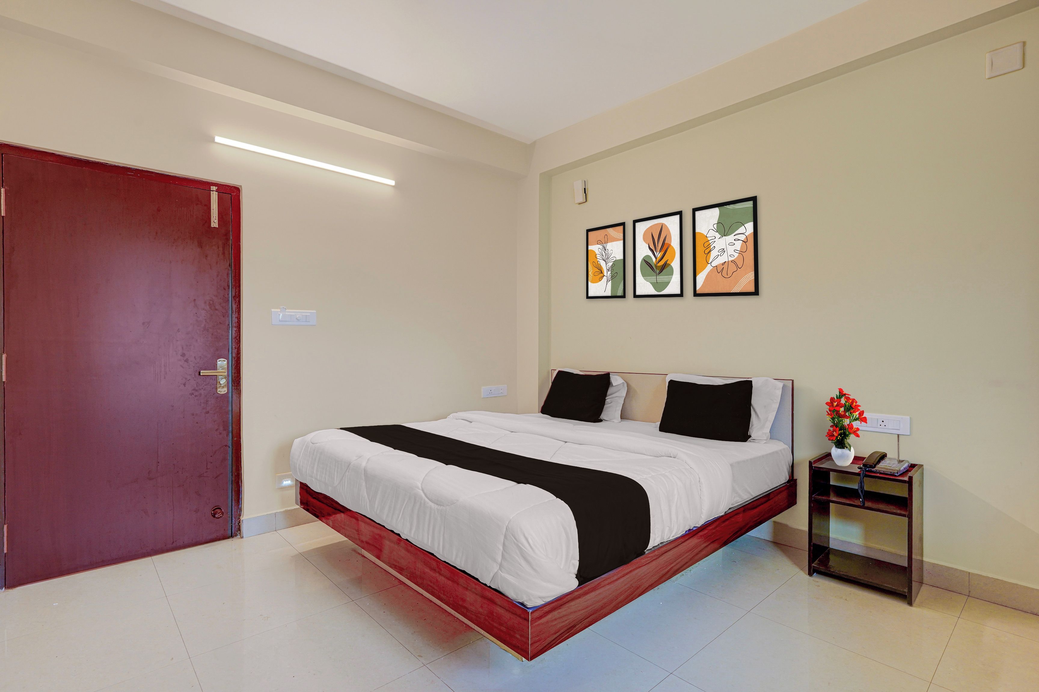 Una habitación de hotel con cama, mesita de noche, toma de corriente y puerta.