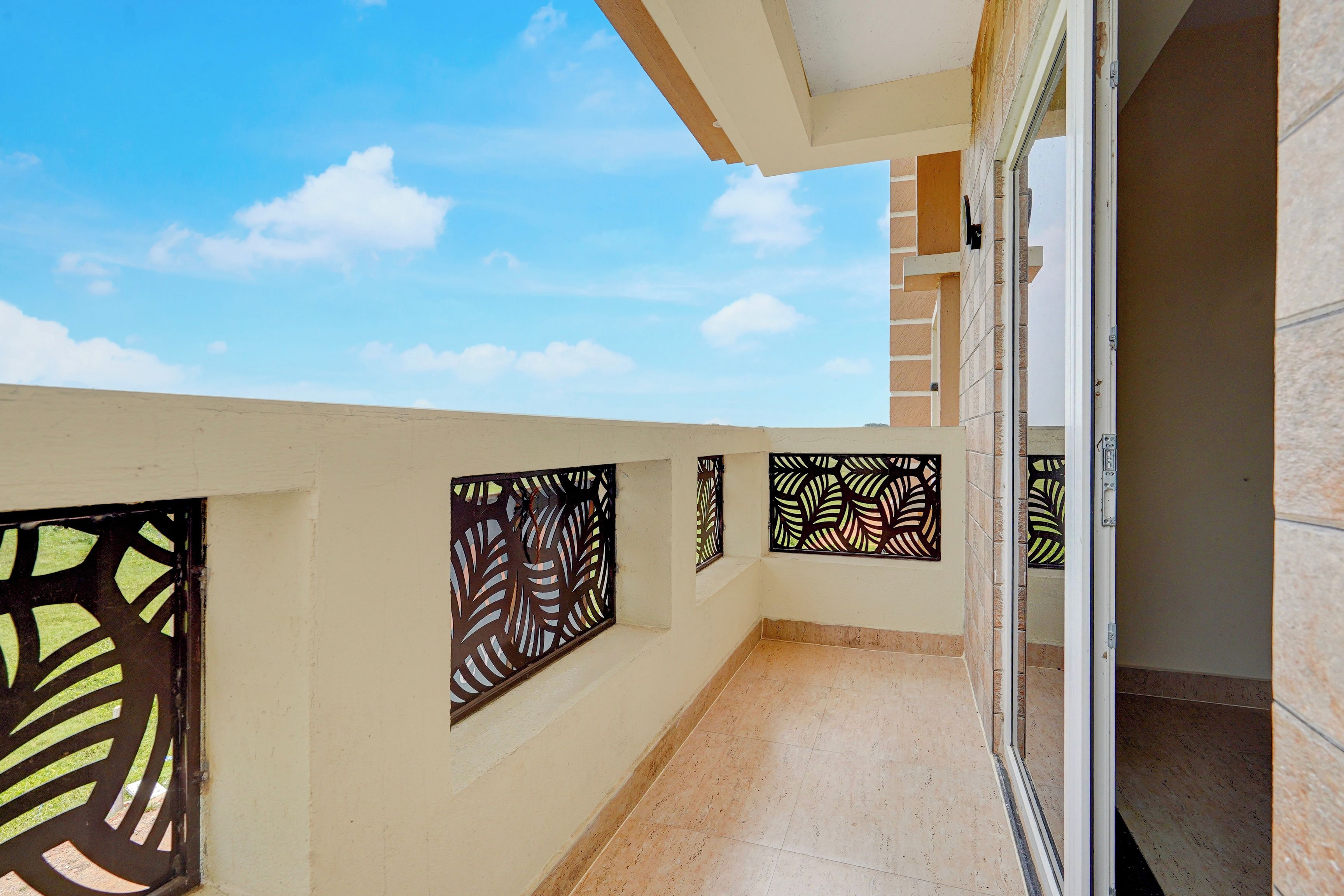 Un balcón con suelo de baldosas, una puerta y paneles metálicos decorativos.
