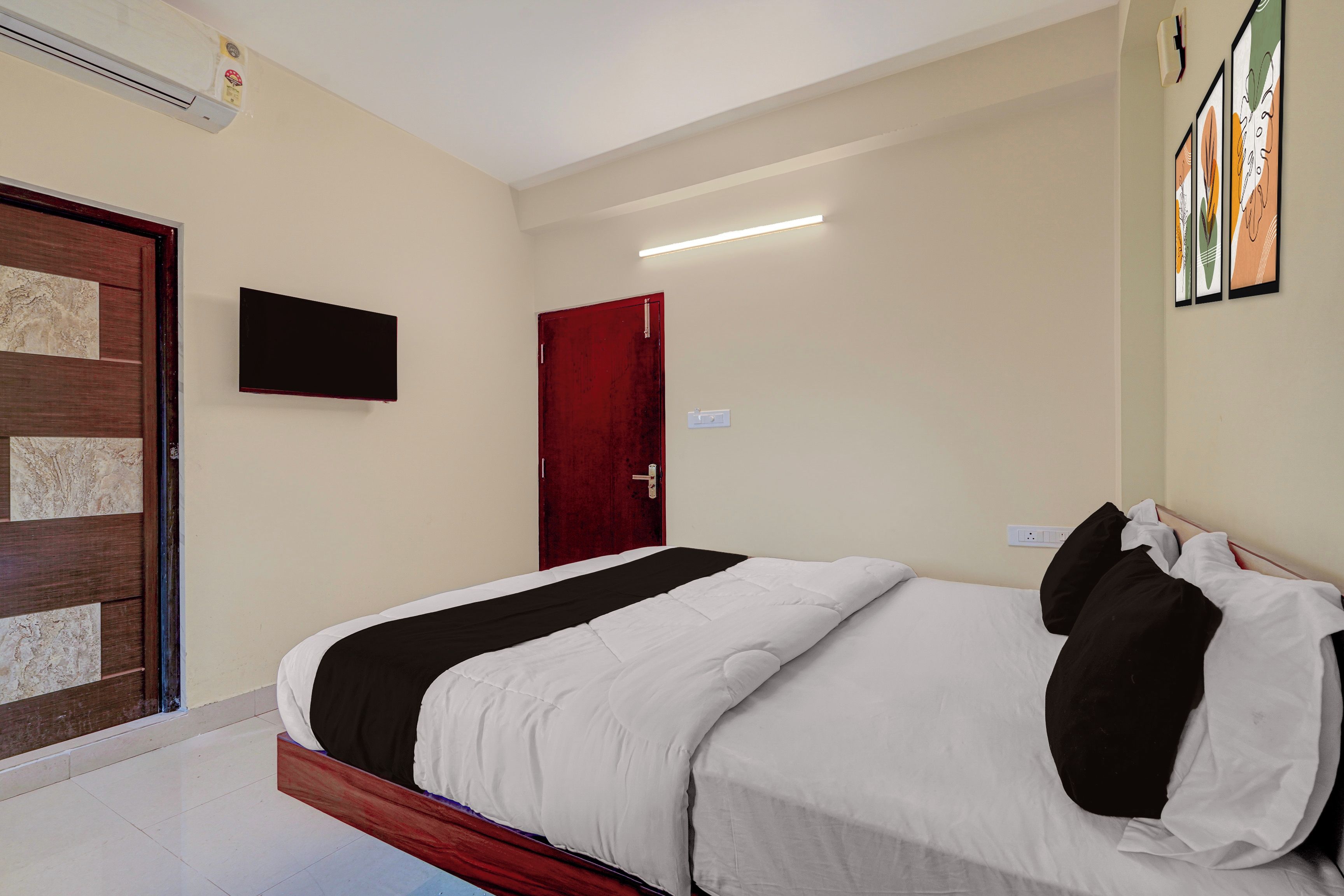 A hotel room with a bed, a television mounted on the wall, and a door.