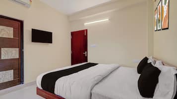 Ett hotellrum med en säng, en tv som är monterad på väggen och en dörr.