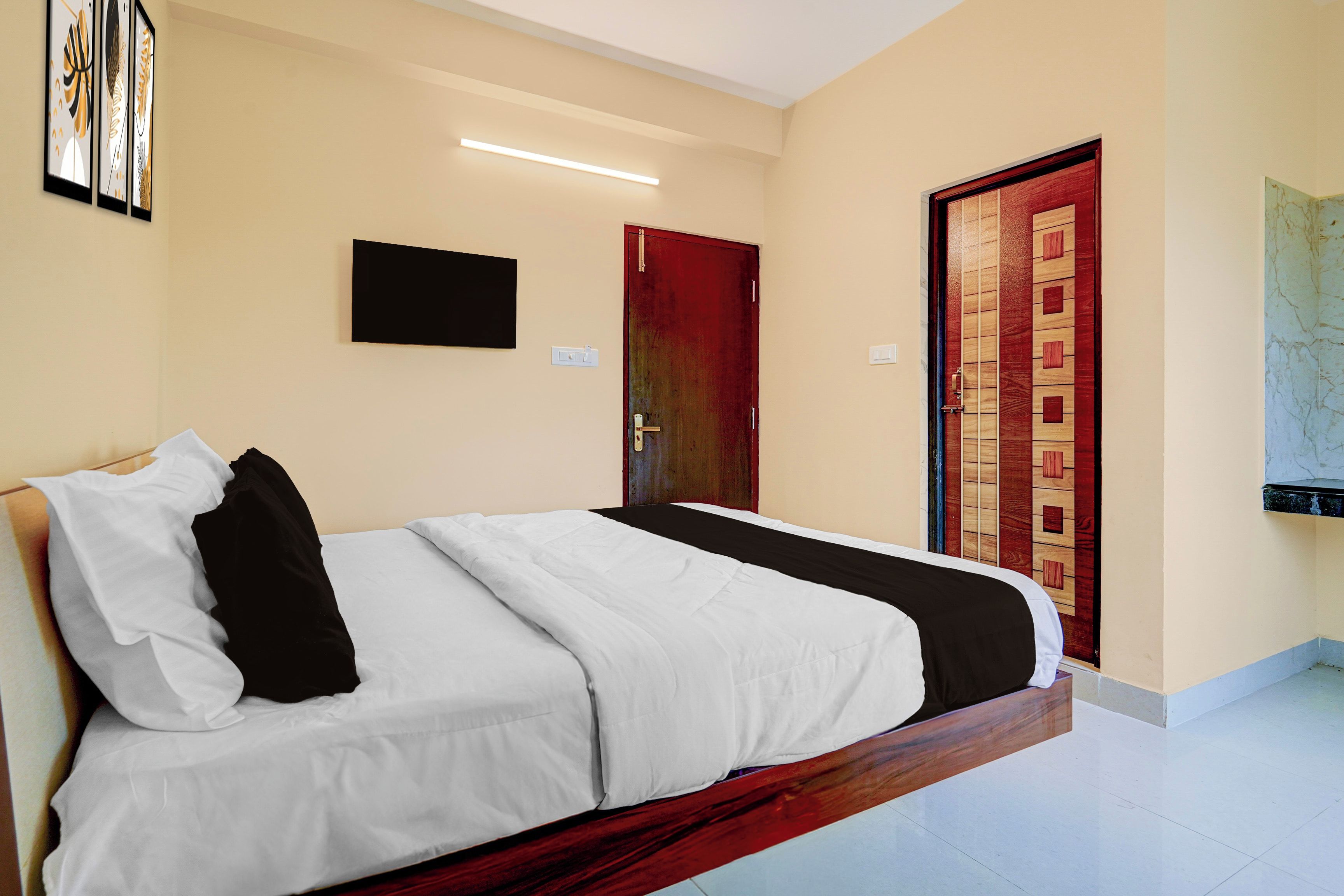 A hotel room with a bed, a door, and a wall-mounted television.