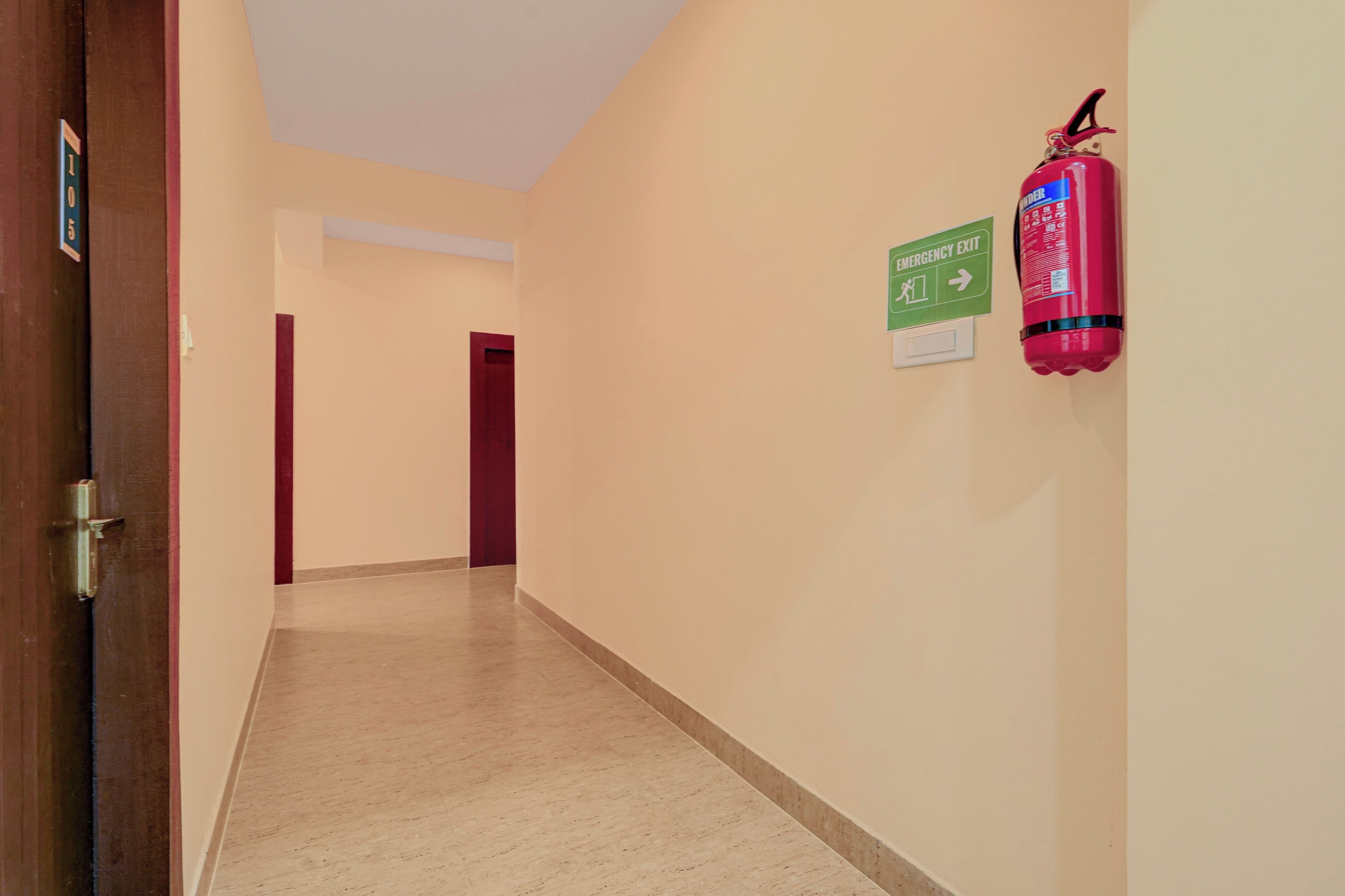 A hallway with a fire extinguisher mounted on the wall and an emergency exit sign.