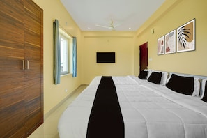 A bedroom with a large bed, a wooden wardrobe, a ceiling fan, and a flat-screen TV. - Hotel O AIIMS Bhubaneshwar (Bhubaneshwar)