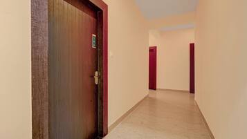 A corridor with a wooden door, beige walls, and a tiled floor.