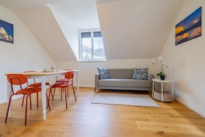 Ein Loft-Zimmer mit Essbereich, einer Couch und einem kleinen Tisch mit Pflanze.
