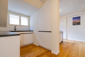 A kitchen with white cabinets, a black countertop, and a window with blinds. - The Cloud  Apartment (Zurigo)