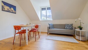 A room with a dining table and chairs, a sofa, a window, and a plant. - The Cloud  Apartment (Zurigo)