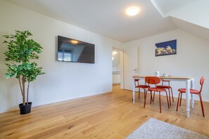 Ein zeitgemäßer Wohnbereich mit Essbereich, einem Blumentopf und einem Flachbildfernseher.