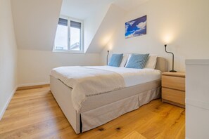 A bedroom with a bed, a nightstand, a lamp, a window, and a wall-mounted picture. - The Cloud  Apartment (Zurigo)