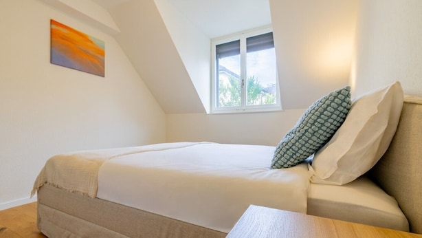 A bedroom with a bed, a window, a painting, and a wooden table. - The Cloud  Apartment (Zurigo)