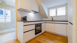 A modern kitchen with white cabinets, a black countertop, and a wooden floor. - The Cloud  Apartment (Zurigo)