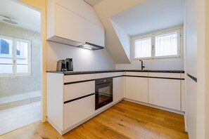 Eine moderne Küche mit weißen Schränken, einer schwarzen Arbeitsplatte und einem Holzboden.