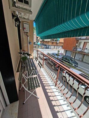 Ein Balkon mit Metallgeländer, einem Klapptisch und Blick auf die Straße.