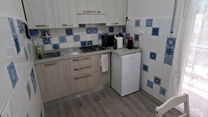 A compact kitchen with white cabinets, a gas stove, a microwave, and a small refrigerator. - On vacation but with all the comforts of home, just a 5-minute walk from the beach (Recco)