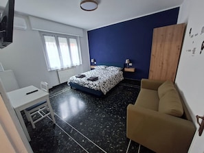 A bedroom with a bed, a desk, a chair, a sofa, a window, and a wall-mounted air conditioner. - On vacation but with all the comforts of home, just a 5-minute walk from the beach (Recco)