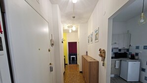 A narrow hallway with a wooden cabinet, a white refrigerator, and a microwave in a kitchen area. - On vacation but with all the comforts of home, just a 5-minute walk from the beach (Recco)