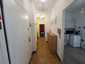 Ein schmaler Flur mit einem Holzschrank, einem weißen Kühlschrank und einer Mikrowelle in einer Küchenzeile.