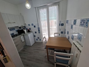 A compact kitchen with a dining area, featuring a refrigerator, stove, and a dining table with chairs. - On vacation but with all the comforts of home, just a 5-minute walk from the beach (Recco)