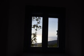 A window with a view of a landscape, including trees and a distant horizon. - Avgonima Sunset Medvial Suite (Chios)