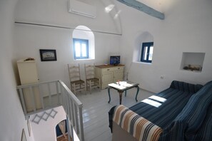 A room with a bed, a desk, two chairs, a small table, and a crib. - Avgonima Sunset Medvial Suite (Chios)