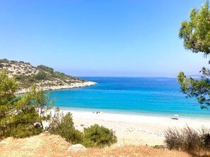 A coastal landscape with a beach, clear blue sea, and sparse vegetation. - Avgonima Joy Medvial Suite (Chios)