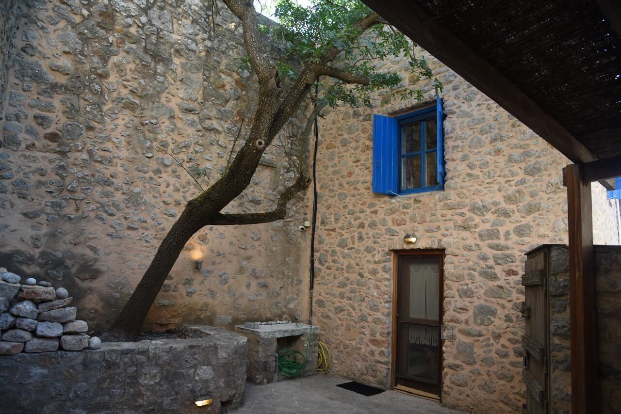 Un edifici de pedra amb una porta de fusta i una finestra blava.