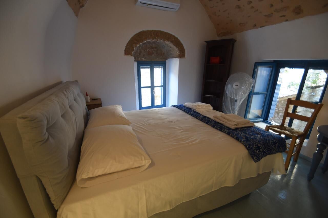 A bedroom with a bed, a chair, a wardrobe, and a window.
