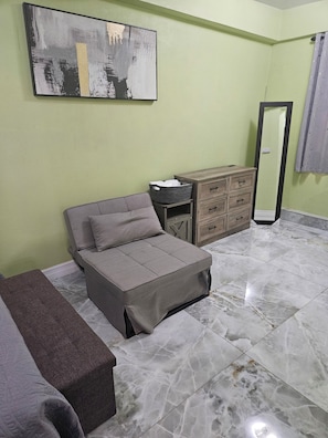 A bedroom with a bed, a dresser, a mirror, and a painting on the wall.