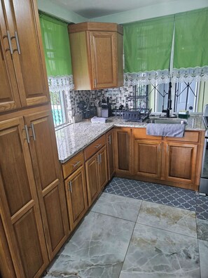 A kitchen with wooden cabinets, a granite countertop, and a tiled backsplash. - Wonderful 1-bedroom house with AC in charming Marigot (Marigot)