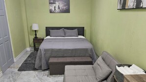 A bedroom with a bed, a sofa, a nightstand, a lamp, and a ceiling fan. - Wonderful 1-bedroom house with AC in charming Marigot (Marigot)