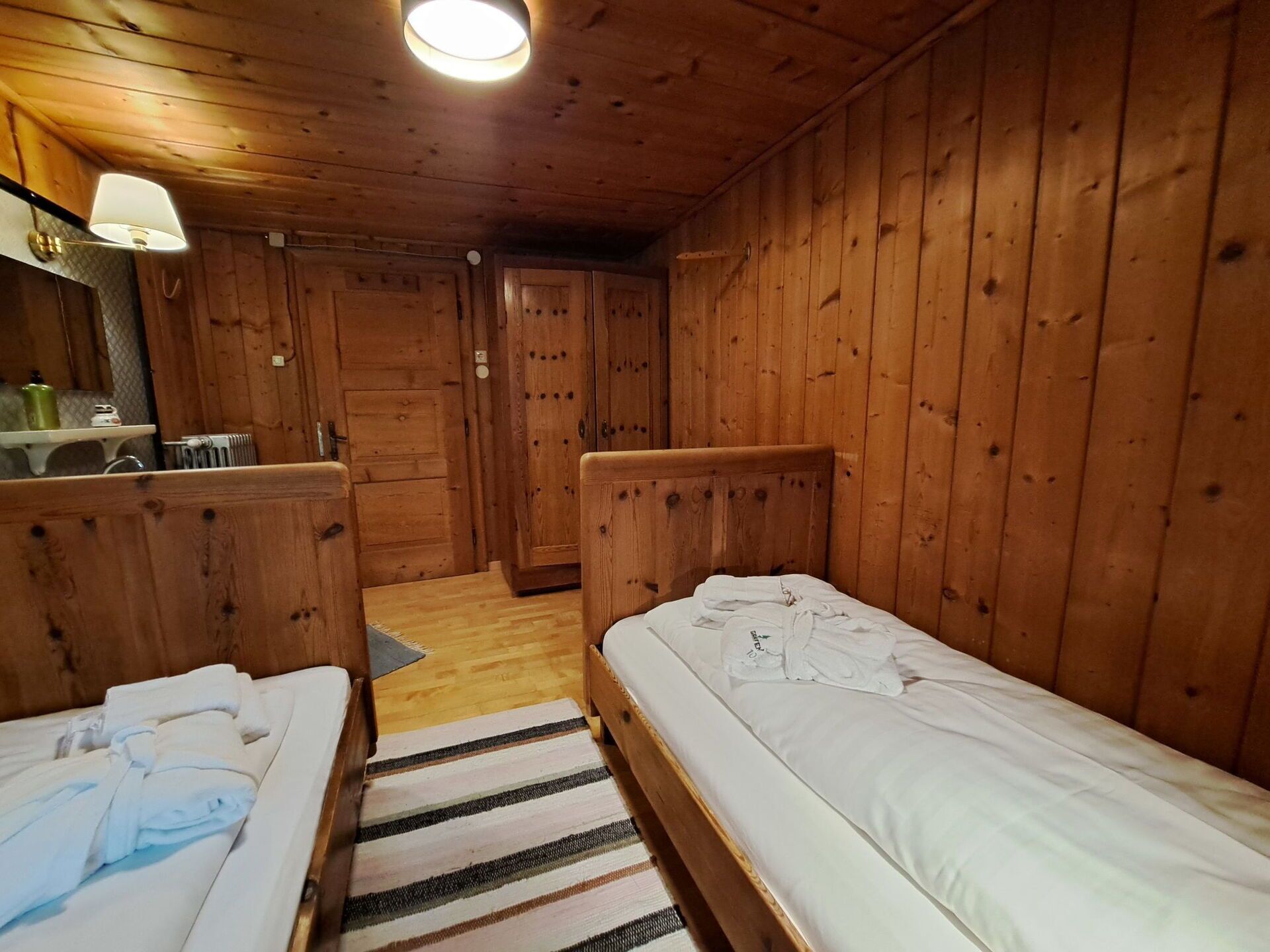 Ein Holzhütten-Zimmer mit zwei Betten, einem kleinen Tisch und einem Spiegel.