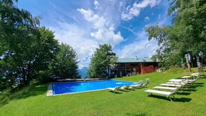 A swimming pool with lounge chairs, surrounded by a grassy area and trees, with a building in the background. - Wonderful private villa for 17 guests with WIFI, TV and terrace (Pill)